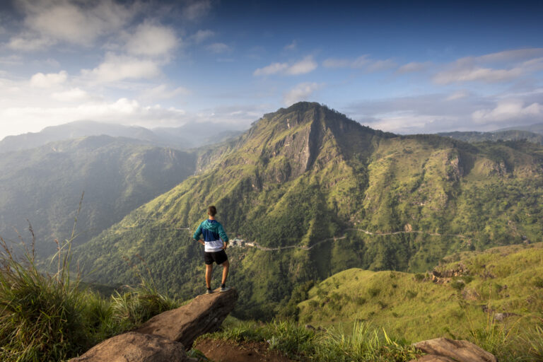 Tourist on Little Adams Peak facing Ella Rock and the Ella Gap in the highlands of Sri Lanka